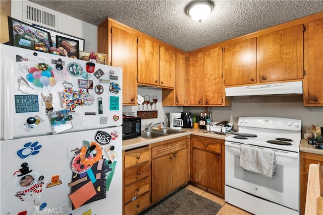 351 W 19th St, Merced, CA 95340 - kitchen with white appliances, under cabinet range hood, a textured ceiling, light countertops, and brown cabinets