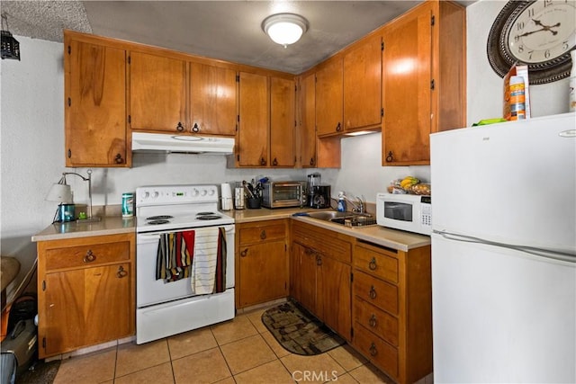 351 W 19th St, Merced, CA 95340 - kitchen with white appliances, under cabinet range hood, brown cabinets, light countertops, and light tile patterned floors