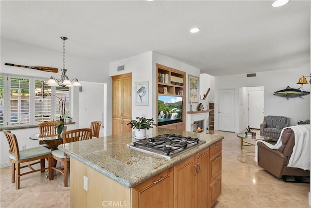 23256 Arelo Ct, Laguna Niguel, CA 92677 - kitchen featuring stainless steel gas cooktop, open floor plan, a center island, a chandelier, and light stone counters