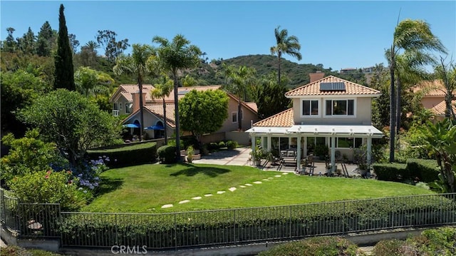 23256 Arelo Ct, Laguna Niguel, CA 92677 - rear view of property featuring a fenced backyard, a patio area, roof mounted solar panels, a tile roof, and stucco siding
