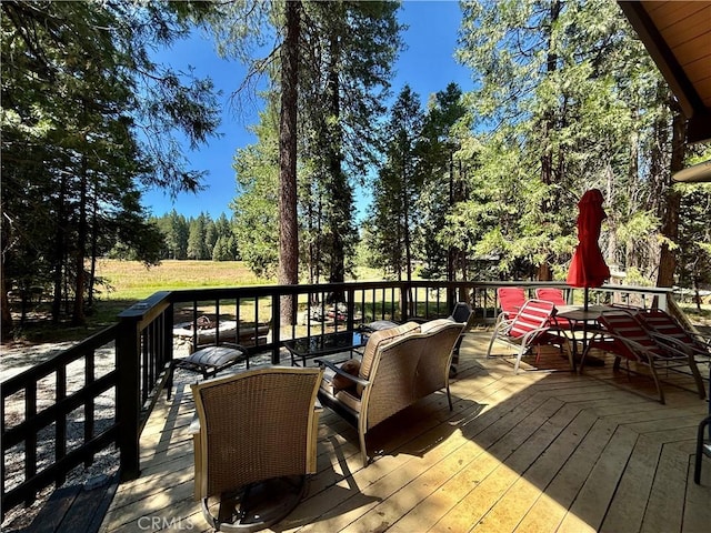 9312 Mountain Meadow Rd, Shingletown, CA 96088 - wooden terrace featuring an outdoor hangout area and view of wooded area