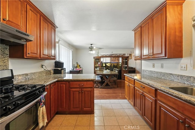 11813 Colima Rd, Whittier, CA 90604 - kitchen with stainless steel gas stove, under cabinet range hood, ceiling fan, light tile patterned floors, and a peninsula