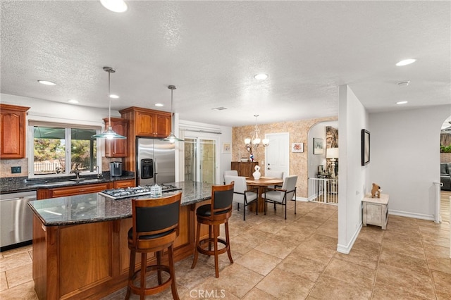 19082 Tecumseh Rd, Apple Valley, CA 92307 - kitchen featuring stainless steel appliances, a center island, a textured ceiling, a chandelier, and tasteful backsplash
