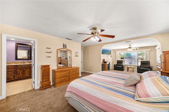 19082 Tecumseh Rd, Apple Valley, CA 92307 - bedroom with arched walkways, light colored carpet, connected bathroom, and a ceiling fan