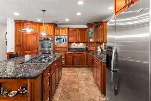 19082 Tecumseh Rd, Apple Valley, CA 92307 - kitchen with stainless steel appliances, brown cabinetry, recessed lighting, hanging light fixtures, and dark stone counters