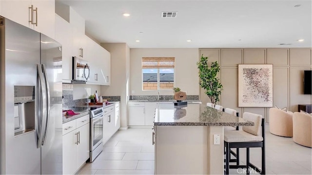 7599 Taylor Ave, Hesperia, CA 92345 - kitchen with appliances with stainless steel finishes, a kitchen island, a breakfast bar, dark stone countertops, and recessed lighting