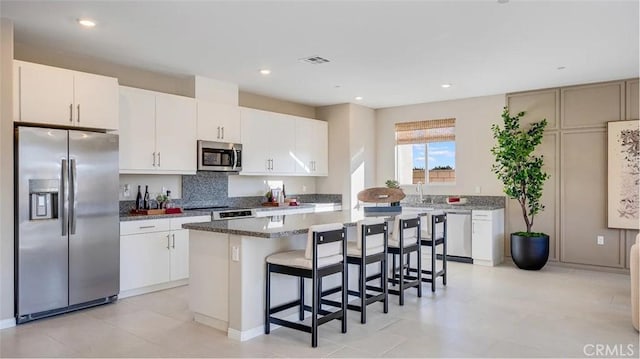 7599 Taylor Ave, Hesperia, CA 92345 - kitchen with stainless steel appliances, a kitchen island, a kitchen breakfast bar, decorative backsplash, and white cabinetry