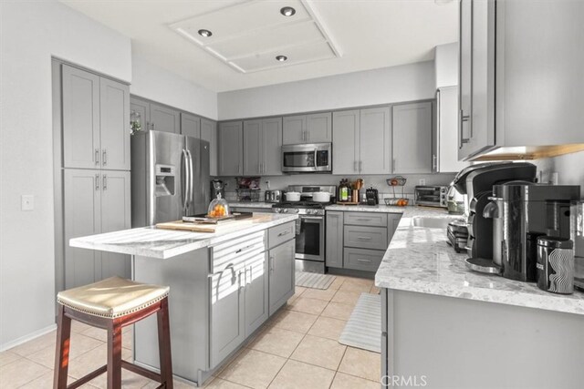 32110 Camino Herencia, Temecula, CA 92592 - kitchen with stainless steel appliances, gray cabinets, light stone countertops, and a kitchen island