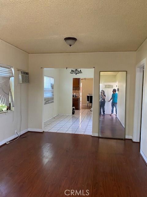 1618 W Burnett, Long Beach, CA 90810 - unfurnished room featuring a textured ceiling, wood finished floors, and a wall unit AC