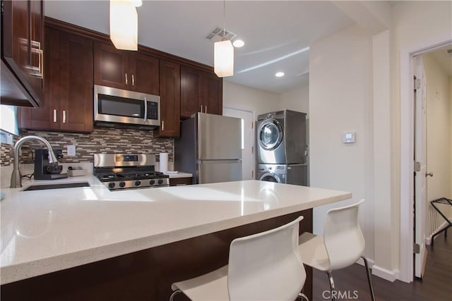 239 W Hillcrest Blvd, Inglewood, CA 90301 - kitchen with stainless steel appliances, stacked washing machine and dryer, tasteful backsplash, a peninsula, and a kitchen breakfast bar