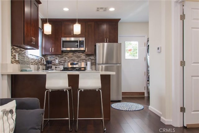 239 W Hillcrest Blvd, Inglewood, CA 90301 - kitchen with appliances with stainless steel finishes, stacked washer and clothes dryer, a peninsula, tasteful backsplash, and light countertops