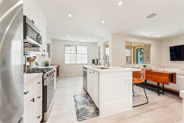 304 Floral Vw, Irvine, CA 92618 - kitchen featuring appliances with stainless steel finishes, open floor plan, light countertops, white cabinetry, and a kitchen island with sink