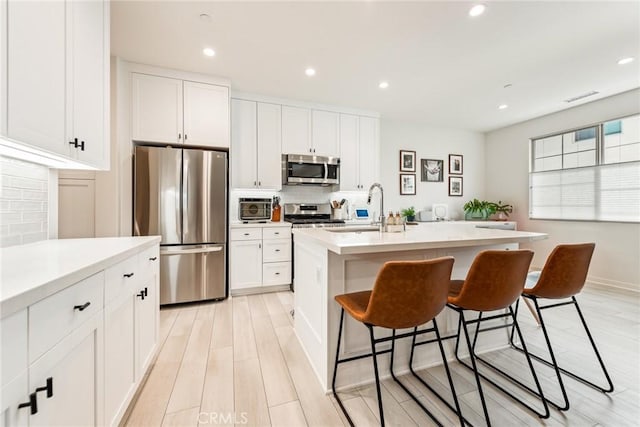 304 Floral Vw, Irvine, CA 92618 - kitchen with appliances with stainless steel finishes, a breakfast bar area, backsplash, white cabinets, and recessed lighting