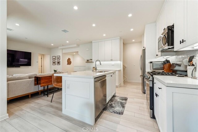 304 Floral Vw, Irvine, CA 92618 - kitchen featuring stainless steel appliances, an island with sink, decorative backsplash, white cabinets, and recessed lighting