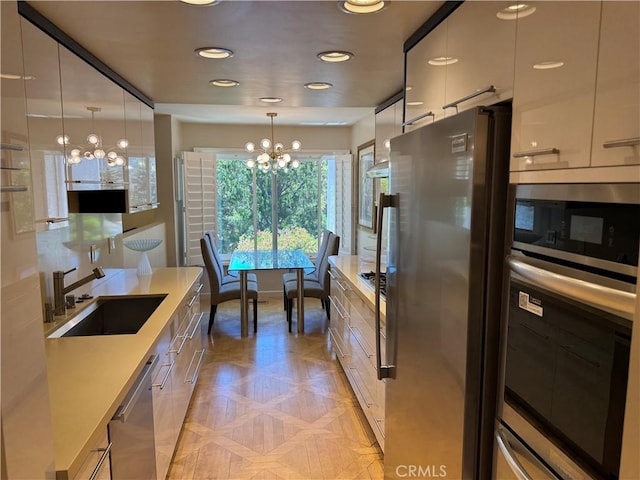 1688 Palisades Dr, Pacific Palisades, CA 90272 - kitchen featuring stainless steel appliances, a chandelier, modern cabinets, decorative light fixtures, and light countertops