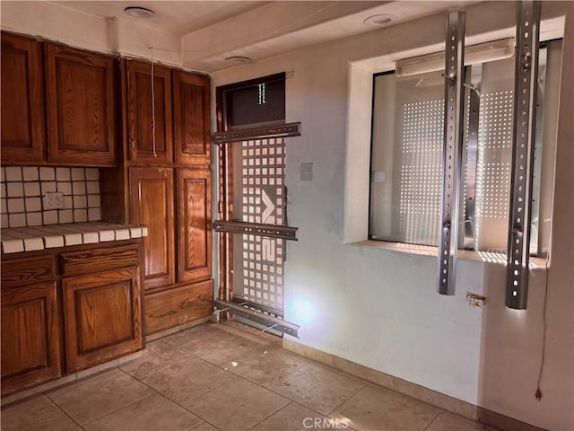 73455 Helms Rd, Desert Hot Springs, CA 92241 - kitchen with tile countertops, light tile patterned flooring, backsplash, and brown cabinets