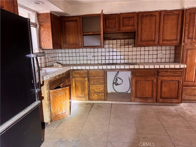 73455 Helms Rd, Desert Hot Springs, CA 92241 - kitchen featuring freestanding refrigerator, tile counters, and decorative backsplash