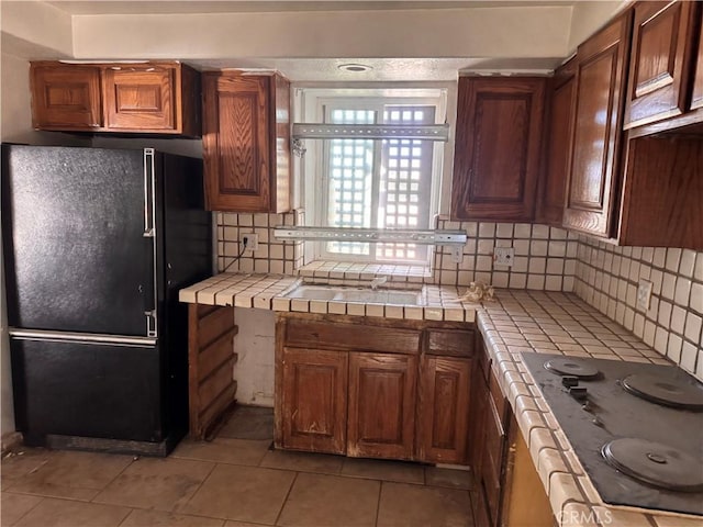 73455 Helms Rd, Desert Hot Springs, CA 92241 - kitchen with freestanding refrigerator, tile counters, electric stovetop, light tile patterned flooring, and tasteful backsplash