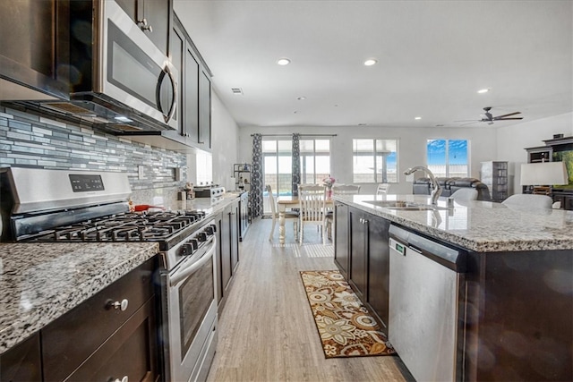 1246 Venice Ave, Mentone, CA 92359 - kitchen with appliances with stainless steel finishes, light wood finished floors, recessed lighting, light stone countertops, and a kitchen island with sink
