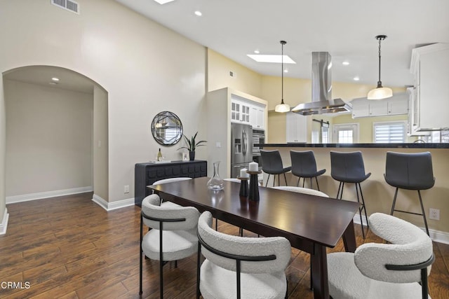 4961 Alcove Ave, Valley Village, CA 91607 - dining room featuring arched walkways, a skylight, dark wood-style flooring, recessed lighting, and a towering ceiling