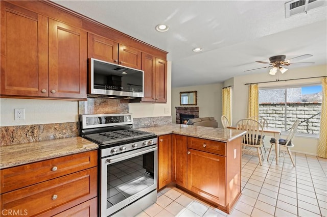 28610 Cloverleaf Pl, Castaic, CA 91384 - kitchen featuring stainless steel gas range oven, a peninsula, ceiling fan, recessed lighting, and brown cabinets