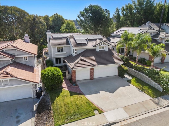 28610 Cloverleaf Pl, Castaic, CA 91384 - view of front of home featuring driveway, a tile roof, roof mounted solar panels, brick siding, and an attached garage