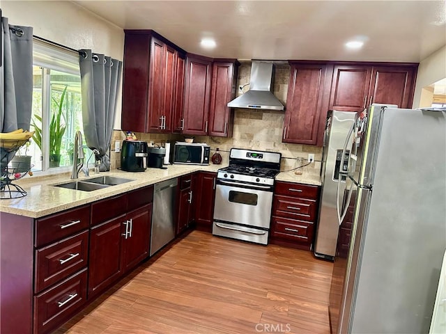 3210 S Center St, Santa Ana, CA 92704 - kitchen featuring appliances with stainless steel finishes, wall chimney range hood, reddish brown cabinets, light wood-type flooring, and recessed lighting