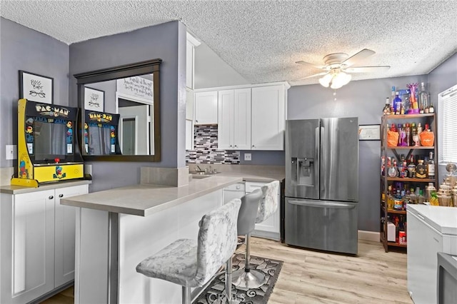 5535 Ackerfield Ave Unit 47, Long Beach, CA 90805 - kitchen with stainless steel fridge, a textured ceiling, a ceiling fan, white cabinetry, and decorative backsplash