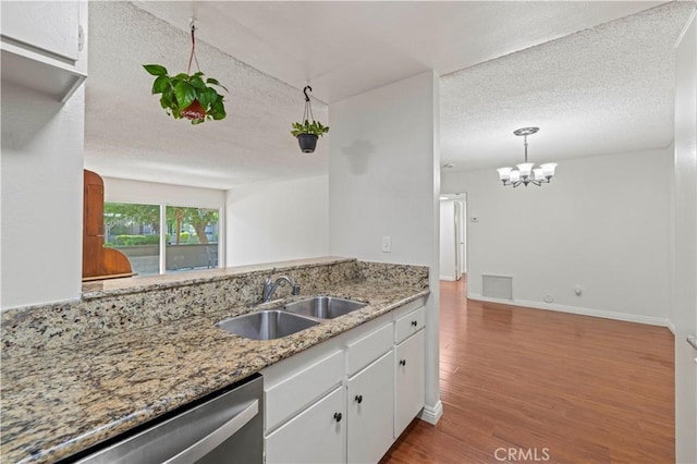 25735 Hogan Dr Unit E11, Valencia, CA 91355 - kitchen featuring a textured ceiling, wood finished floors, a chandelier, white cabinetry, and stainless steel dishwasher