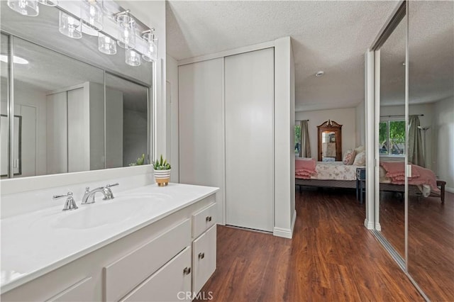 25735 Hogan Dr Unit E11, Valencia, CA 91355 - ensuite bathroom with wood finished floors, vanity, and a textured ceiling