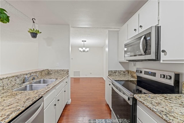 25735 Hogan Dr Unit E11, Valencia, CA 91355 - kitchen featuring appliances with stainless steel finishes, a chandelier, white cabinetry, wood finished floors, and a textured ceiling