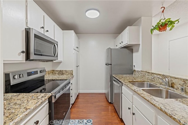 25735 Hogan Dr Unit E11, Valencia, CA 91355 - kitchen with stainless steel appliances, wood finished floors, white cabinets, and light stone counters