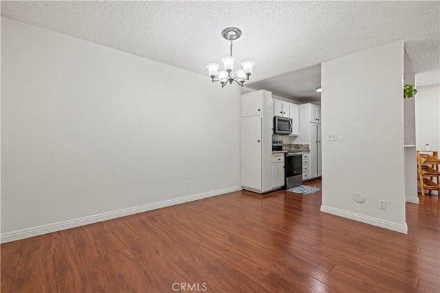 25735 Hogan Dr Unit E11, Valencia, CA 91355 - unfurnished dining area featuring a chandelier, dark wood finished floors, and a textured ceiling
