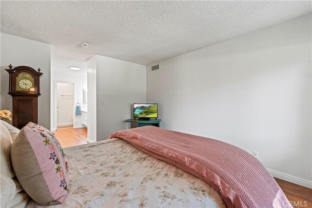 25735 Hogan Dr Unit E11, Valencia, CA 91355 - bedroom with wood finished floors, a textured ceiling, and connected bathroom