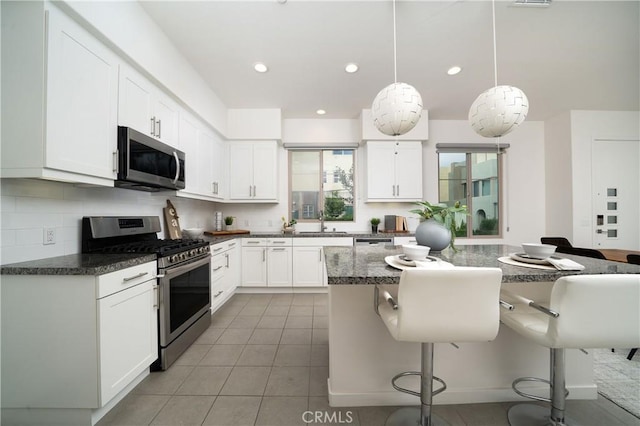 185 Magnet, Irvine, CA 92618 - kitchen featuring appliances with stainless steel finishes, a kitchen bar, white cabinetry, backsplash, and recessed lighting