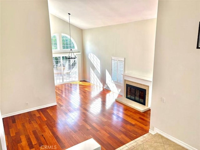 72 Coral Unit 38, Irvine, CA 92614 - unfurnished living room featuring vaulted ceiling, wood finished floors, and a glass covered fireplace