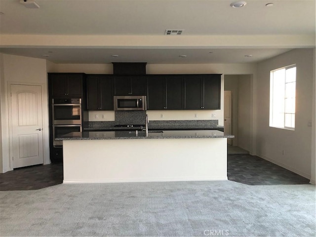 1031 Coriander St, Calimesa, CA 92320 - kitchen with appliances with stainless steel finishes, a center island with sink, carpet floors, and dark stone countertops
