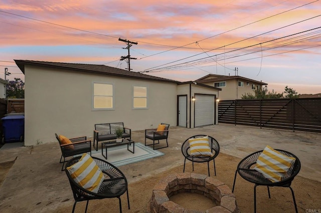 3821 Shiloh Rd, San Diego, CA 92105 - patio terrace at dusk with an outdoor living space with a fire pit, a fenced backyard, a patio area, a garage, and concrete driveway