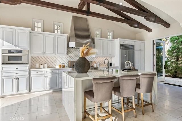 3 Coral Cay, Newport Coast, CA 92657 - kitchen featuring appliances with stainless steel finishes, wall chimney range hood, decorative backsplash, light countertops, and a center island with sink