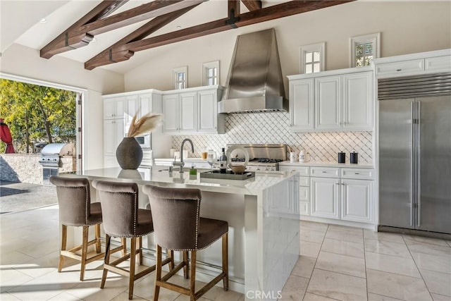 3 Coral Cay, Newport Coast, CA 92657 - kitchen featuring stainless steel built in refrigerator, wall chimney exhaust hood, stove, beamed ceiling, and tasteful backsplash