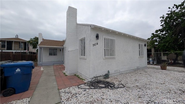 9614 Graham Ave, Los Angeles, CA 90002 - view of side of home featuring stucco siding and a chimney