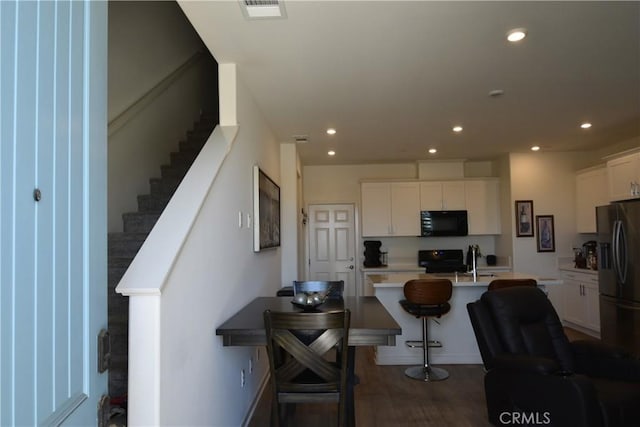 975 W Clover Ave, Rialto, CA 92376 - kitchen with black microwave, stove, refrigerator with ice dispenser, white cabinetry, and recessed lighting