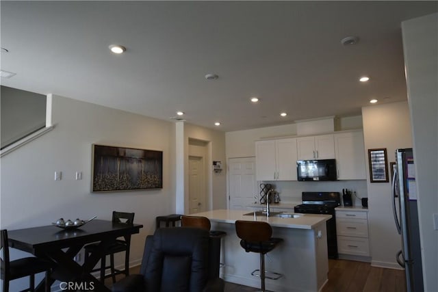 975 W Clover Ave, Rialto, CA 92376 - kitchen featuring black appliances, light countertops, white cabinets, dark wood-style floors, and a center island with sink