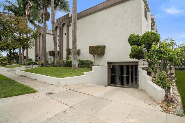 218 E Tamarack Ave Unit 5, Inglewood, CA 90301 - view of side of property with stucco siding, an attached garage, concrete driveway, and a gate