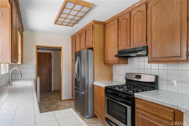 15511 Gramercy Pl, Gardena, CA 90249 - kitchen featuring stainless steel appliances, under cabinet range hood, tile countertops, tasteful backsplash, and brown cabinets