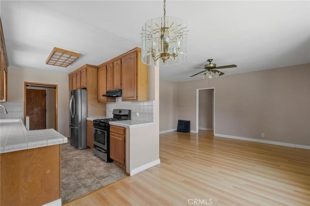 15511 Gramercy Pl, Gardena, CA 90249 - kitchen with range with gas cooktop, freestanding refrigerator, under cabinet range hood, tile countertops, and decorative backsplash