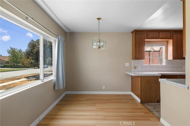 15511 Gramercy Pl, Gardena, CA 90249 - kitchen with tile countertops, light wood-type flooring, backsplash, a chandelier, and brown cabinetry