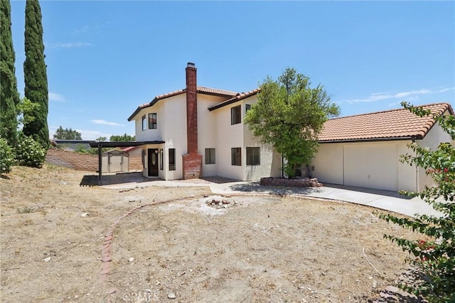 1122 W Galway St, Rialto, CA 92377 - back of house with a chimney, a tiled roof, stucco siding, an outdoor fire pit, and a storage unit