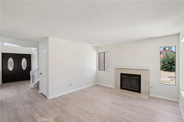 1122 W Galway St, Rialto, CA 92377 - unfurnished living room with a textured ceiling, light wood finished floors, a tile fireplace, and stairway