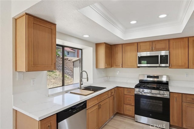 1122 W Galway St, Rialto, CA 92377 - kitchen featuring appliances with stainless steel finishes, a raised ceiling, ornamental molding, brown cabinetry, and light wood finished floors
